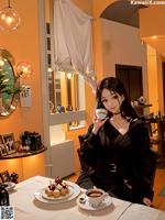 A woman sitting at a table with a cup of coffee.