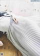 A woman laying on the floor wearing a gray pleated skirt.