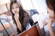 A woman sitting at a desk looking at a computer screen.