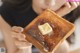 A woman holding a piece of toast with butter on it.