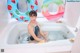 A woman sitting in a bathtub with two inflatable rings.