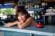 A woman leaning on a counter in a restaurant.