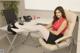 A woman sitting at a desk in an office with her legs crossed.