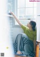 A woman sitting on the floor in front of a window.