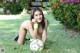 A young woman laying on the grass with a soccer ball.