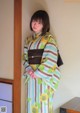 A woman in a kimono standing in front of a wall.