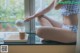 A woman sitting on a window sill with a cup of coffee.